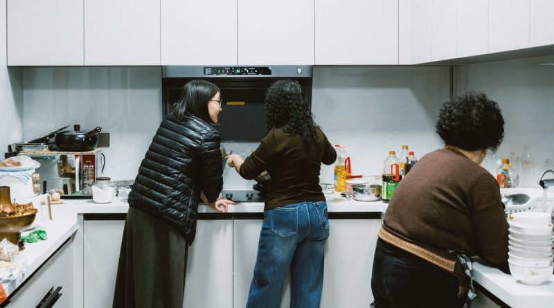 Two adult sisters discussing care for their elderly father in a family kitchen.