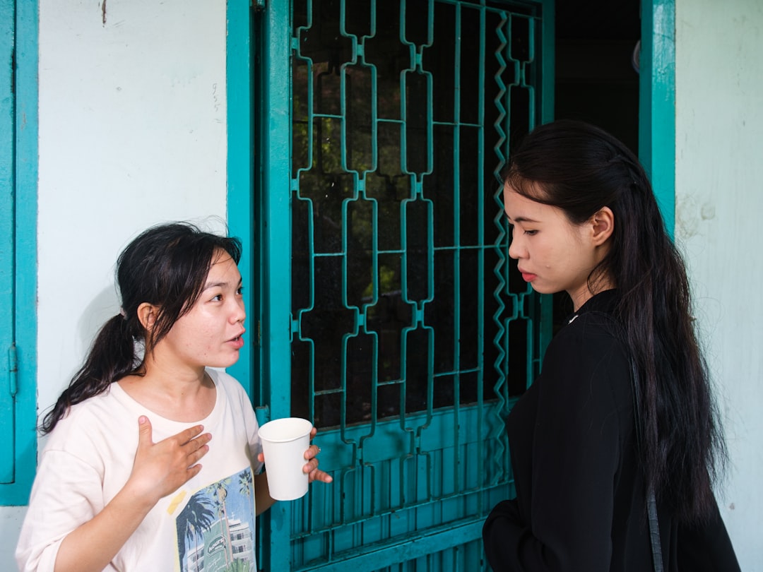 Two adult sisters having a serious conversation outside a family home.