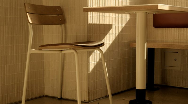 An empty chair beside a dining table in warm afternoon light.