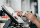 A cashier working with money and receipts at a retail counter.