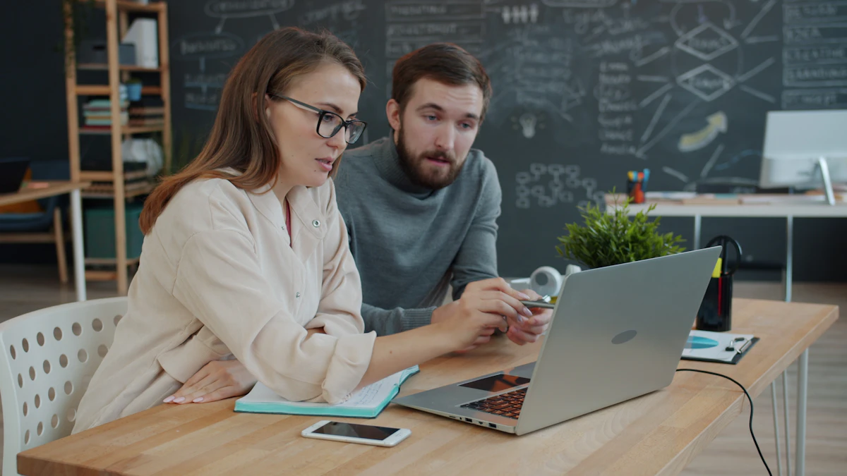 Two colleagues reviewing work together on a laptop in an office.