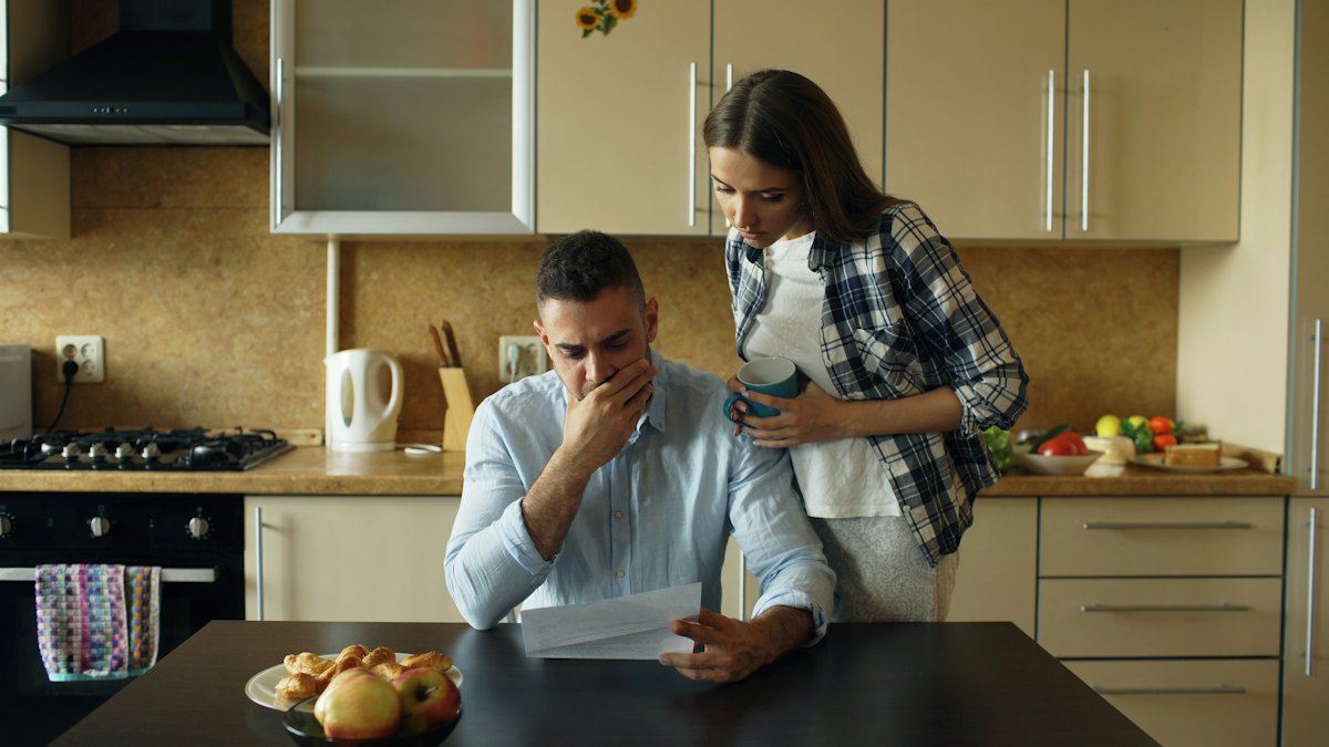 A couple discussing financial documents together at a kitchen table.