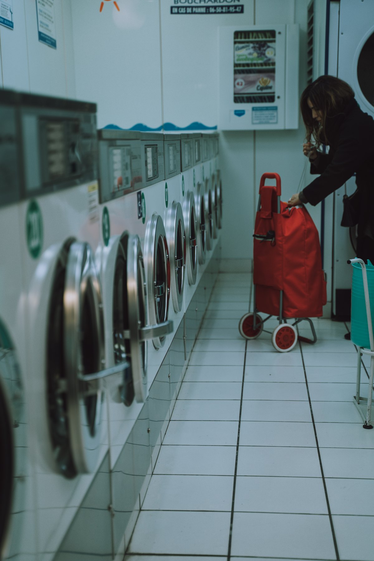 A woman standing inside a neighborhood laundromat.