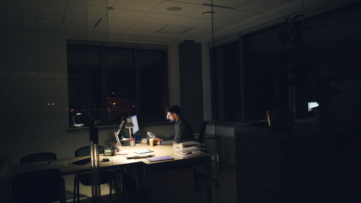 An employee working alone at an office desk late at night.