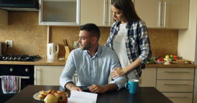 A couple discussing bills at a kitchen table, representing a difficult conversation about family money.