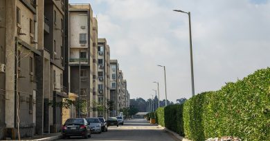A residential street, representing a dispute between neighbors over trash bins and curb space.