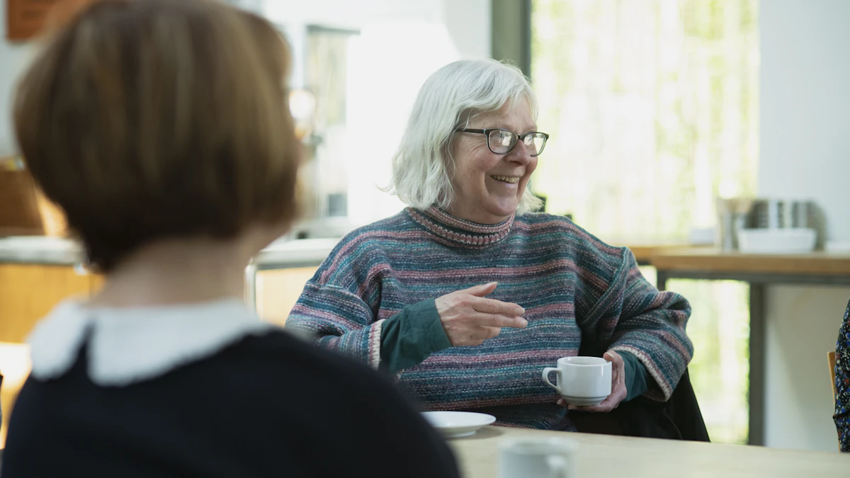 Two older women talking together over coffee at a cafe.