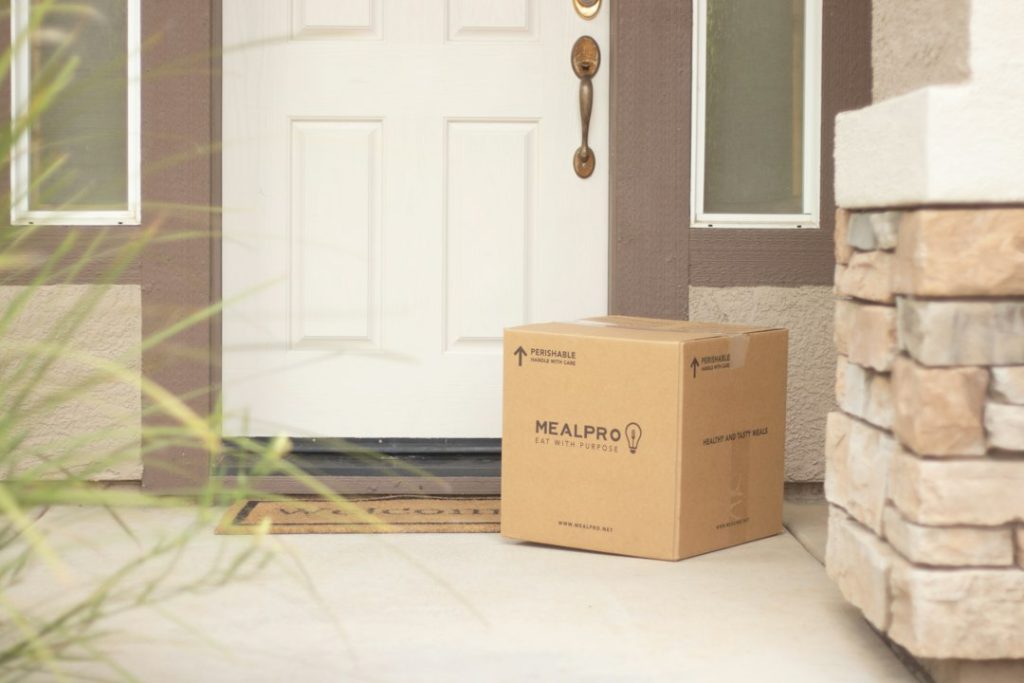 A cardboard package left beside a front door.