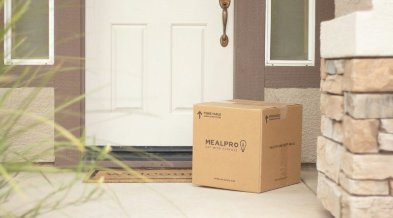 A cardboard package left beside a front door.
