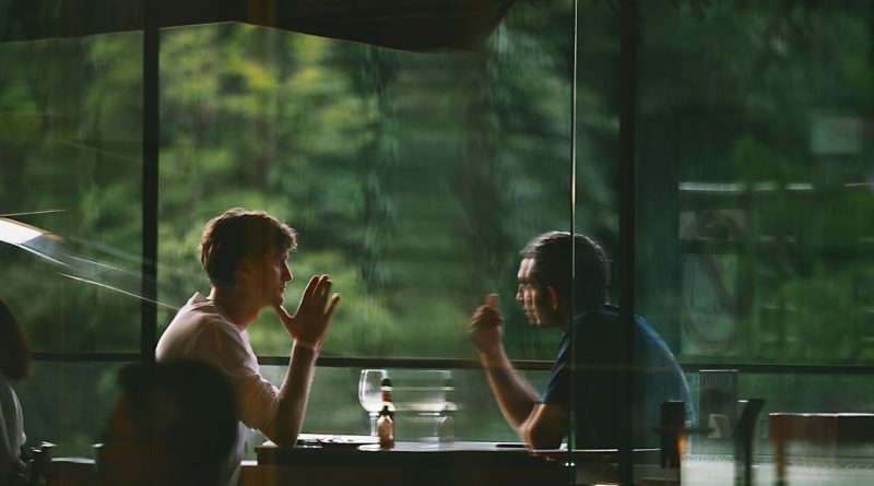A man and his ex-wife talking over documents at a restaurant table during a weekly lunch.