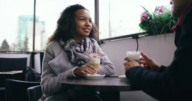 Two adult friends talking together over coffee at a cafe.