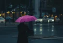 A person walking with an umbrella on a rainy city street.