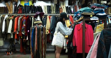 A shopper browsing vintage clothing in a thrift store.