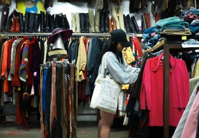 A shopper browsing vintage clothing in a thrift store.