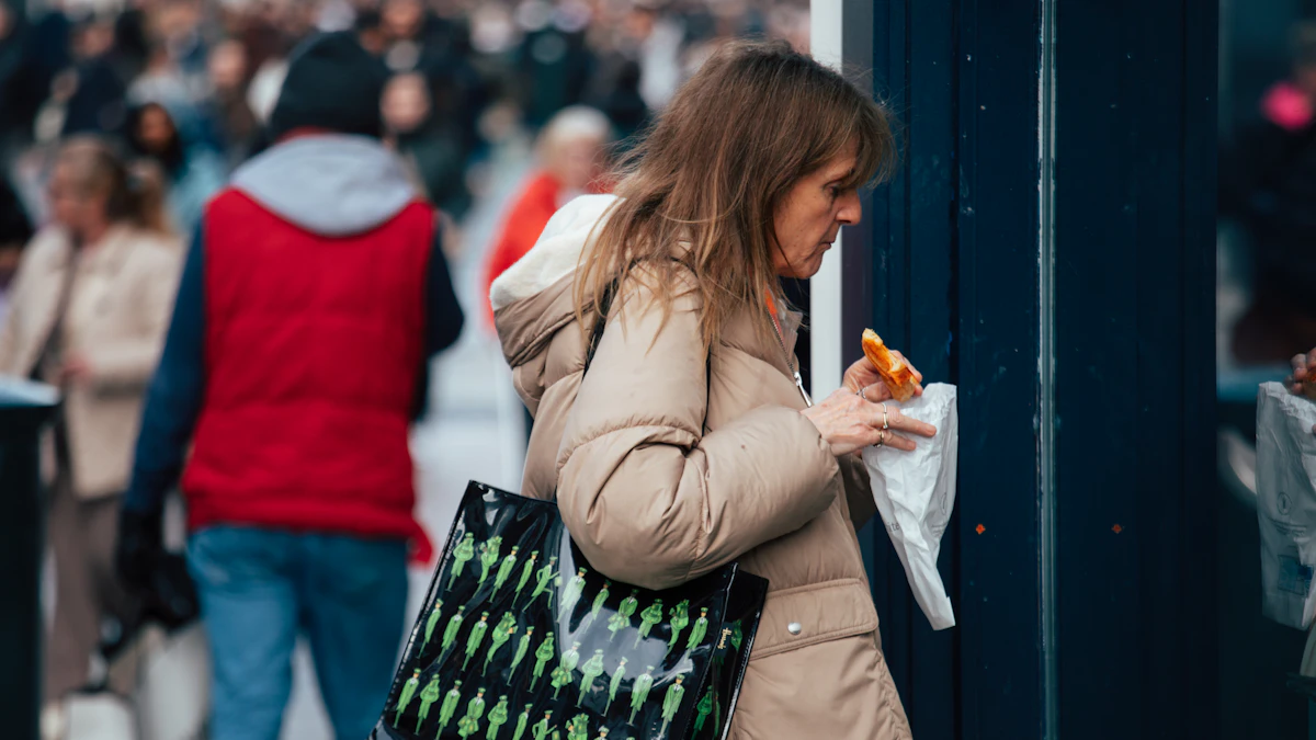 A woman walking along a city sidewalk carrying a bag.