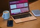 A laptop displaying a work calendar beside a notebook and coffee.